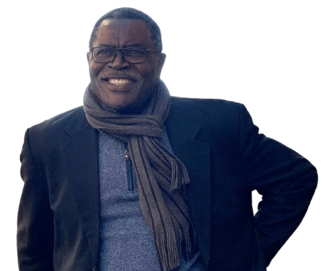Matthew Otasowie wearing glasses and a black suit jacket with a scarf, smiling upwards